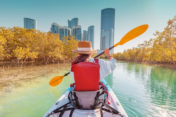 Kayaking through the Eastern Mangroves of Abu Dhabi with the city skyline visible above the trees