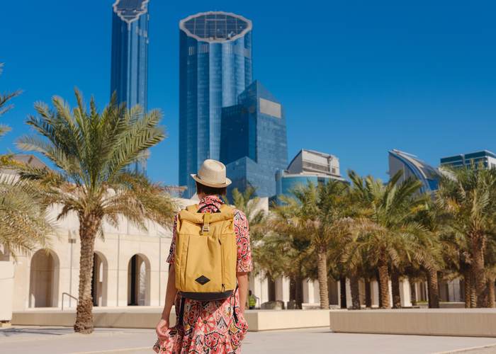 Traveller watching a camel caravan cross the road near Abu Dhabi