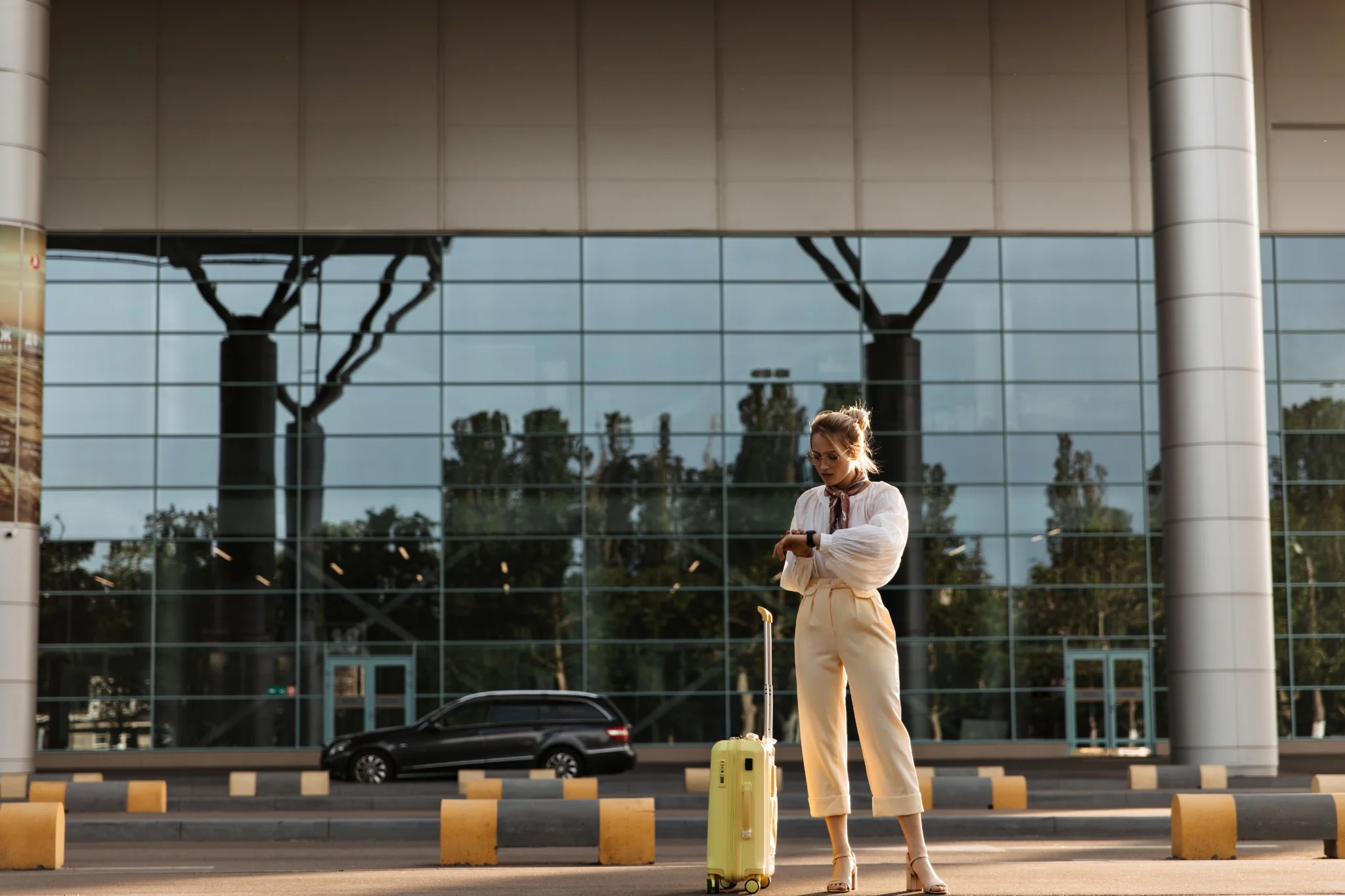 Business traveller walking with luggage beside an airport transfer car