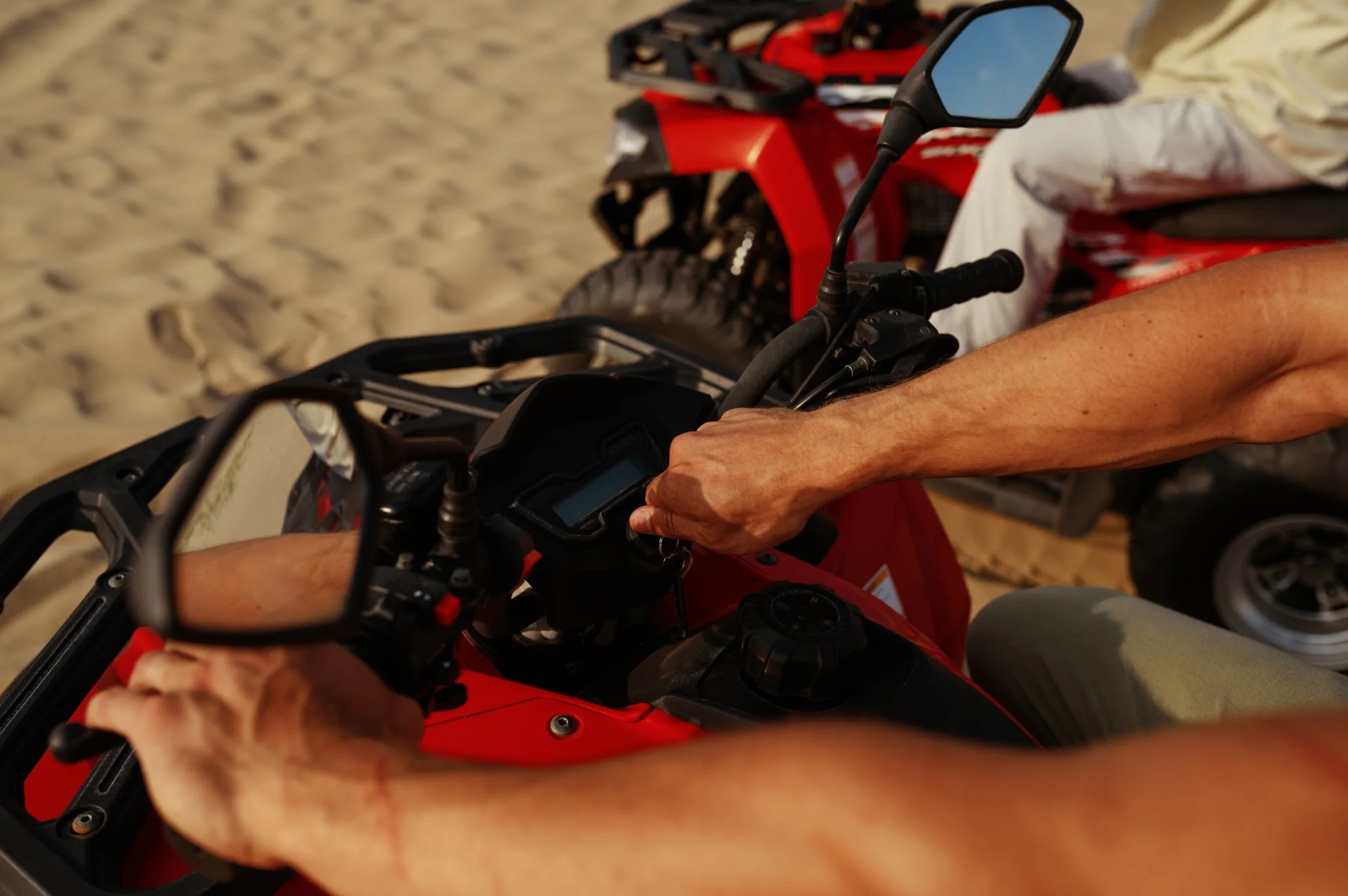 Close-up of riders starting red quad bikes in the desert