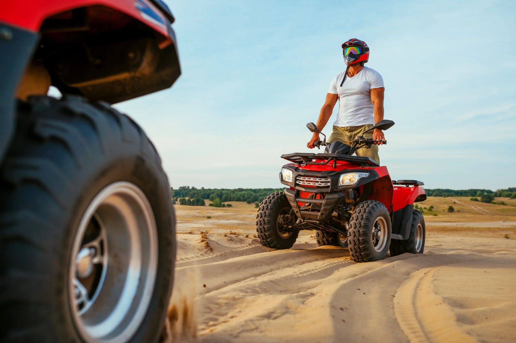 Helmeted rider on a red quad bike in the desert
