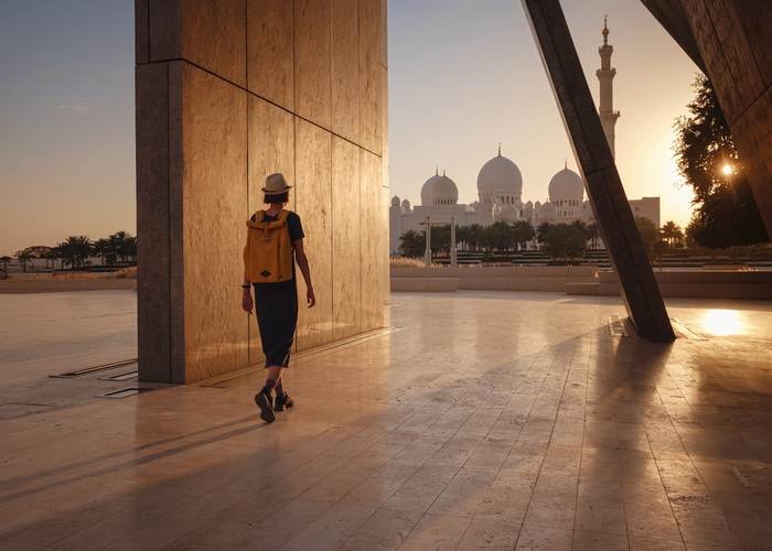 Traveller walking towards Sheikh Zayed Grand Mosque at golden hour