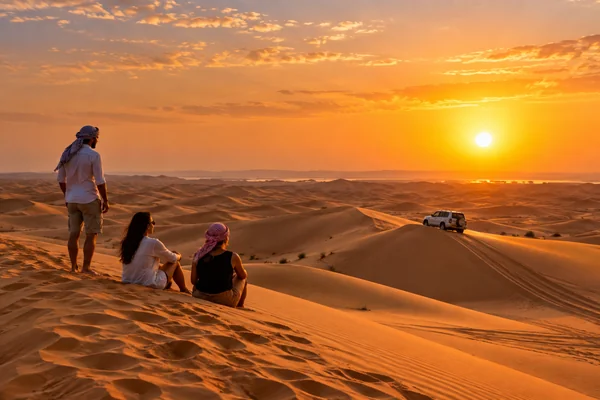 Guests watching the sunset over Abu Dhabi desert dunes during an evening safari