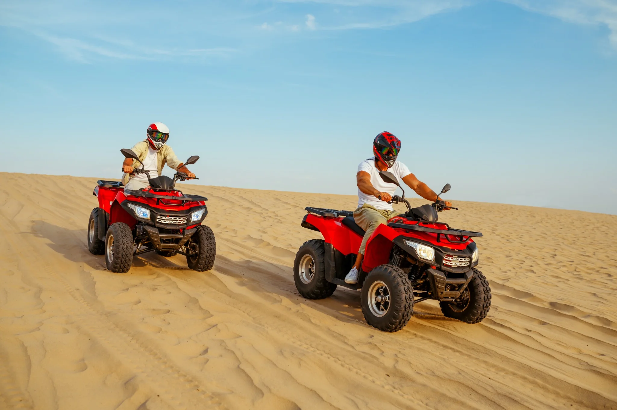 Two riders on red quad bikes in the Abu Dhabi desert
