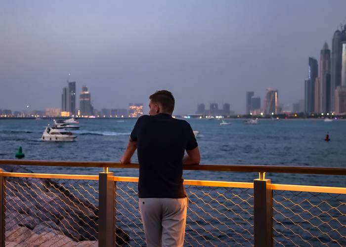 Traveller looking out over the Abu Dhabi waterfront at dusk