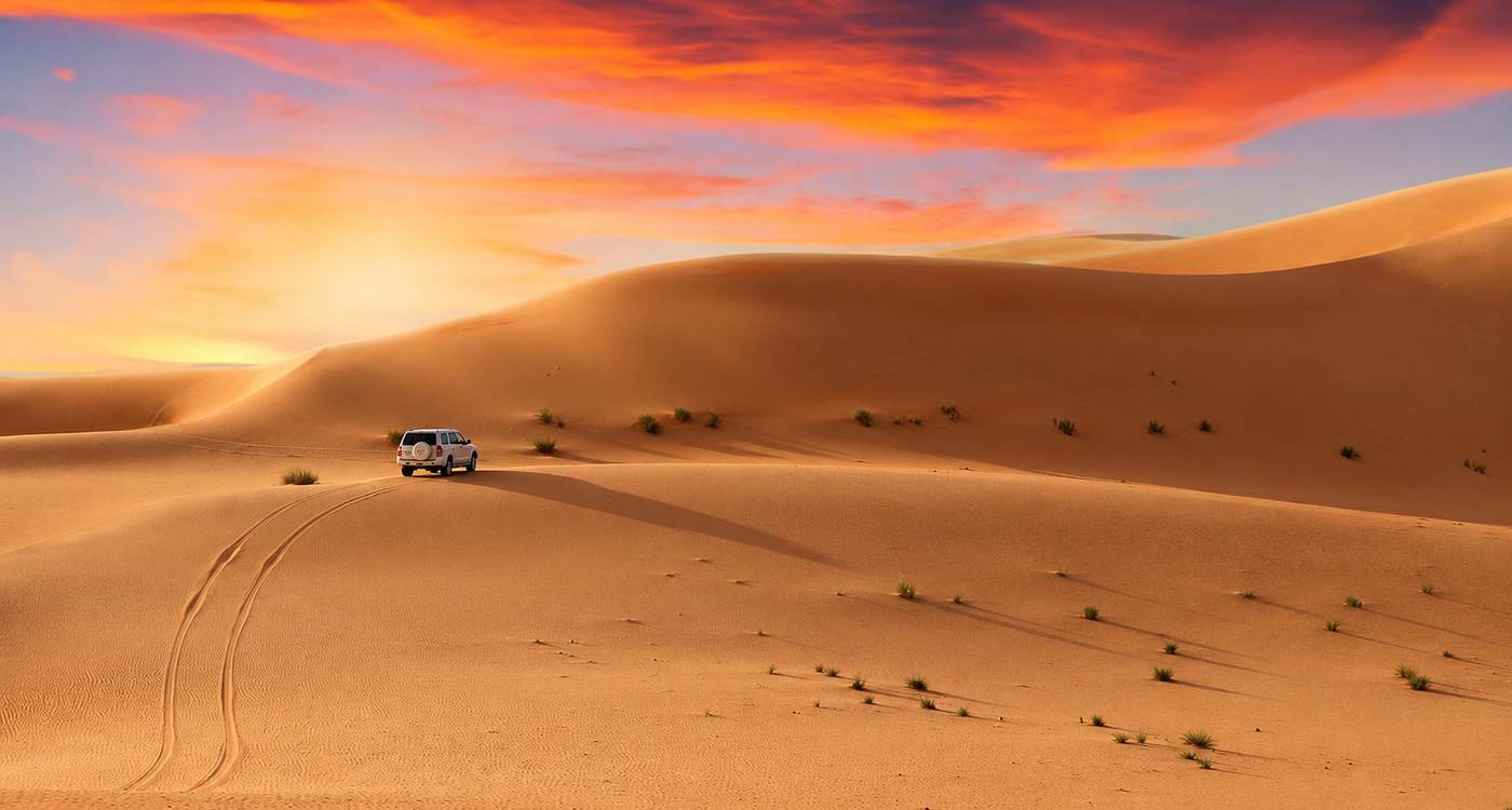 4x4 crossing the Abu Dhabi dunes beneath a dramatic evening sky