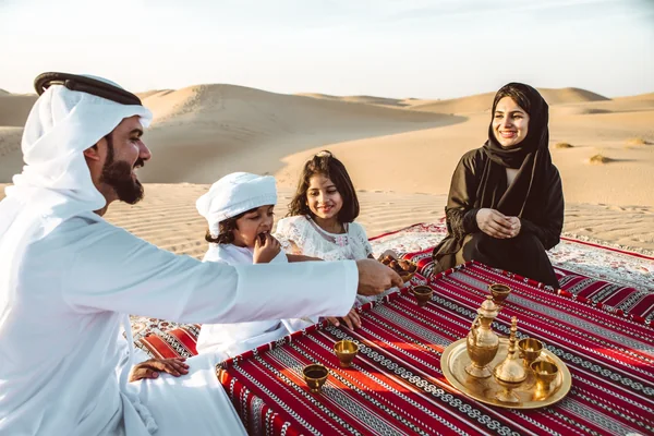 Emirati family sharing Arabic coffee and dates on the dunes during a private Liwa desert camping trip