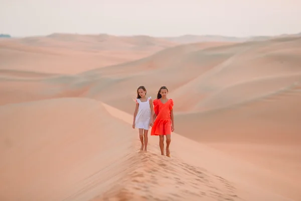 Children walking along a high sand dune during a family-friendly Liwa desert safari