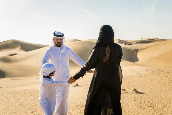 Family holding hands on the Al Khatim dunes during a private morning desert safari in Abu Dhabi