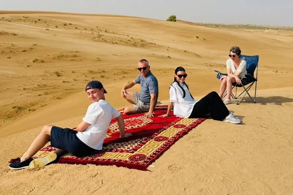 Family holding hands on the Al Khatim dunes during a private morning desert safari in Abu Dhabi