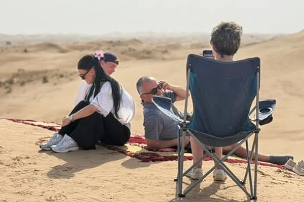 Emirati couple sharing Arabic coffee and dates during a morning desert safari in Abu Dhabi