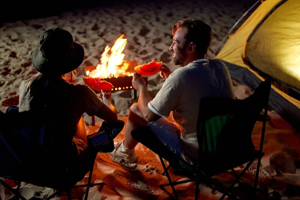 Couple enjoying hot drinks beside a campfire at an Abu Dhabi desert camping site