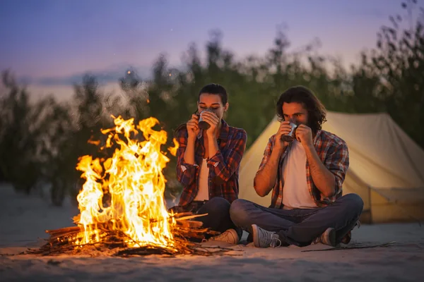Couple taking a selfie beside a campfire during an overnight desert camping experience in Abu Dhabi