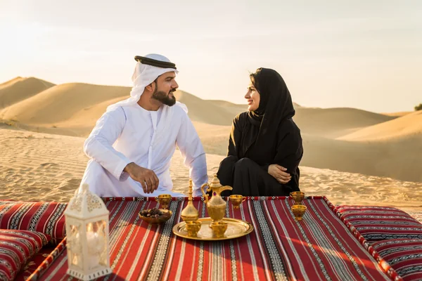 Emirati couple enjoying Arabic coffee on the dunes during a private desert safari in Abu Dhabi